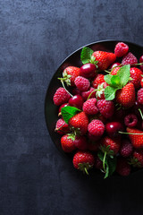 Fresh red ripe berries on black plate