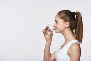 Profile portrait of sporty teen girl drinking clear water looking forward at blank copy space