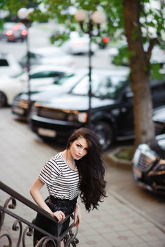 beautiful gorgeous young woman with long hair on evening city street with cars