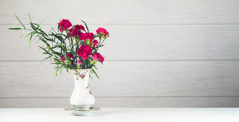 Bouquet of pink carnations in a rustic vase on a white background
