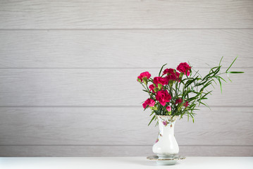Bouquet of pink carnations in a rustic vase on a white background