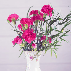Bouquet of pink carnations in a rustic vase on a white background