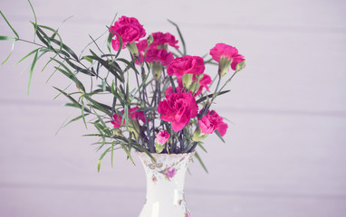 Bouquet of pink carnations in a rustic vase on a white background