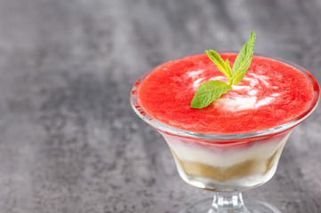 fruit smoothie with a petal in a glass vase on a gray surface.