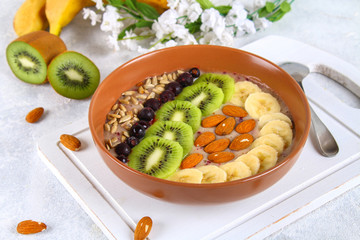 Breakfast berry smoothie bowl topped with bananas, berries, kiwi, almonds and sunflower seeds.