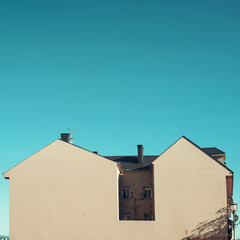 Minimal picture of a house with huge wall without any windows. The building is lighten by the daylight and under a blue intense sky.