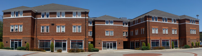 Panorama of brick office building under blue sky. Nobody.