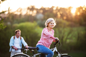 Obraz premium Beautiful senior couple with bicycles outside in spring nature.