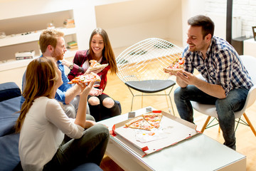 Young friends eating pizza at home and having fun