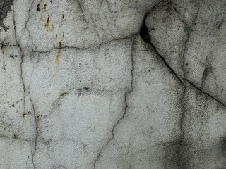 An old rusty wall of a house with cracks on which moss grow