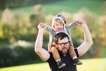 A father with his toddler son outside in spring nature.