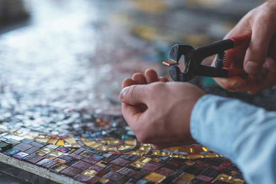 Men's hands cutting mosaic
