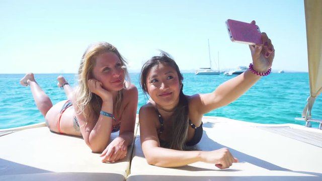 Beautiful young friends relaxed in yatch and taking a selfie