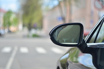 Naklejka premium Car rear view mirror on the city background.