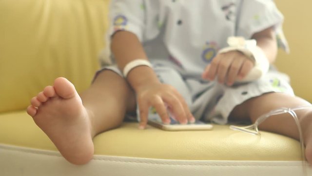 Thai child  playing  smartphone  on chair, focus on child&rsquo;s  feet 