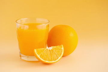 Glass of orange juice freshly squeezed on an orange background