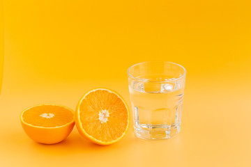 Detox Water with orange in a glass on an orange background
