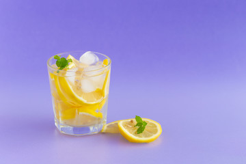 Detox Water with lemon in a glass on a purple background