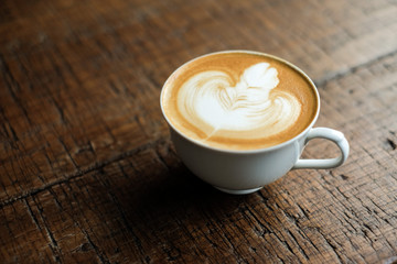 A Cup of hot latte art  in a white cup coffee  on wooden table background