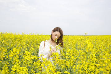 Fototapeta premium Portrait of fashionable young woman in the yellow flowers field 