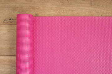 Pink yoga mat on a wooden background. Fitness concept, active lifestyle, body care concept. Wood Background
