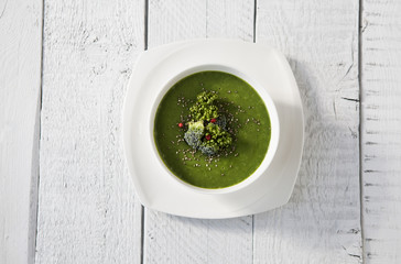 Spinach green soup with broccoli in white bowl top view