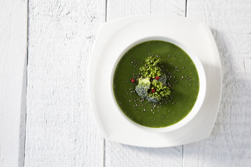 Spinach green soup with broccoli in white bowl top view