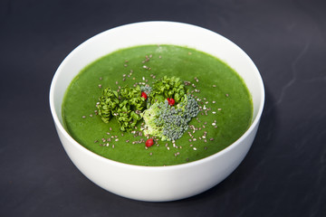 Spinach green soup with broccoli in white bowl top view