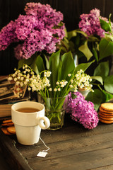 Obraz na płótnie Canvas A cup of hot tea and a bouquet of lilac flowers (a date) Food background