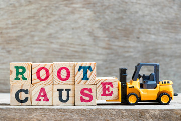 Toy forklift hold letter block e to complete word root cause on wood background