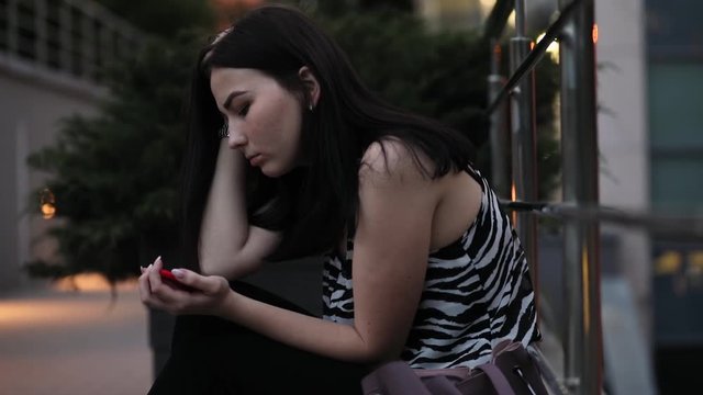 Teenage girl sadly looking down to smartphone