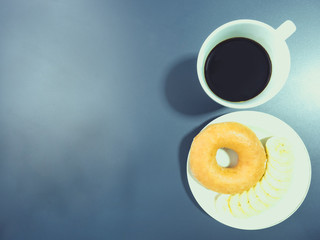 Obraz na płótnie Canvas flat lay from black coffee in white cup with banana and donut from morning time with blue background and copy space