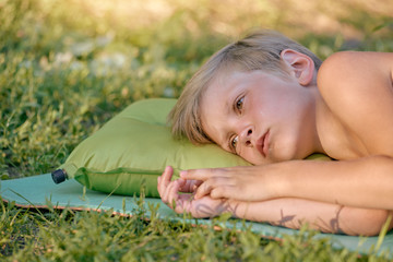 Portrait of cute young boy lying on green grass