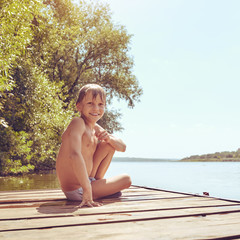 Young boy swimming and sunbathing during summer holidays, image with square aspect ratio and warm...