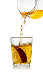 Freshly squeezed apple juice pours into glass with an apple slic