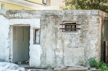 Naklejka na ściany i meble Small house near building with damaged door and walls with bullet holes used as improvised hidden prison with bars on the window in the war zone by terrorists in the Syria