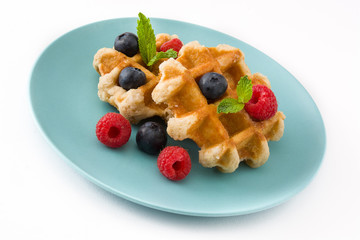 Traditional belgian waffles with blueberries and raspberries, isolated on white background. 

