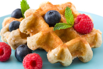 Traditional belgian waffles with blueberries and raspberries, isolated on white background. Close up

