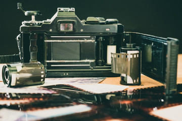 Roll of 35 mm photographic film with old camera on wooden table.