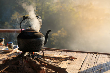 Ancient iron kettle or teapot on fire in the cottage floor, smoke from teapot.