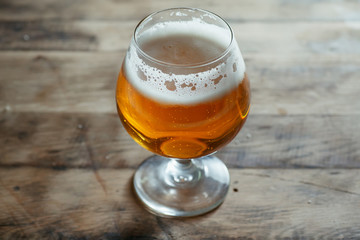 Snifter beer glass on a wooden barrel