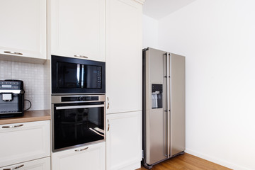 Modern kitchen area, wooden floor with modern refrigerator and appliances