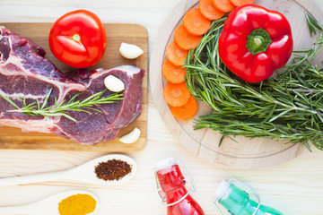 Raw beef meat on the wooden cutting board with vegetables, rosemary and spices. Top view. Close up. Food concept.