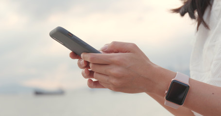 Hand holding cellphone with the sunset sea background