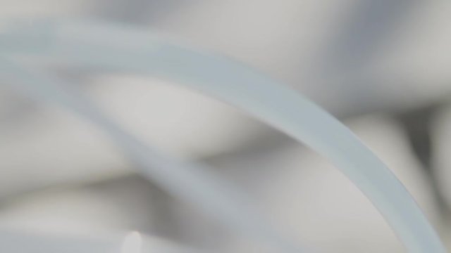 Extreme closeup in slow motion of maple sap moving through plastic tube to a tote to make maple syrup.