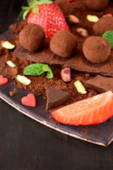 Chocolate truffles covered with cacao powder surrounded by strawberries and mint