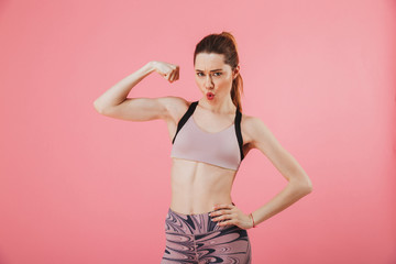 Pleased sportswoman posing with arm on hip while showing bicep