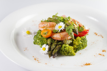 Prawns, asparagus and broccoli with edible daisy flowers. Selective focus.