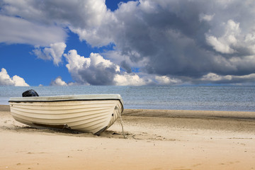 Einzelnes weißes  Boot am Strand an der Ostsee im Hintergrund dunkle Wolken