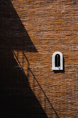 Windows on an ancient brick wall. Has a triangular shadow across.